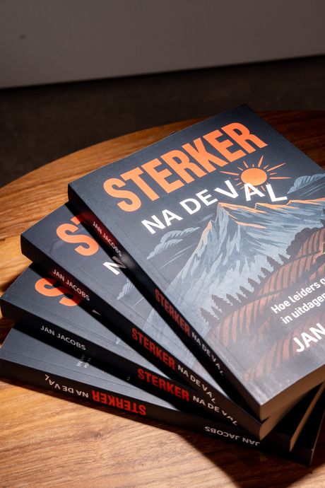 Een stapel exemplaren van Sterker na de val op een houten tafel